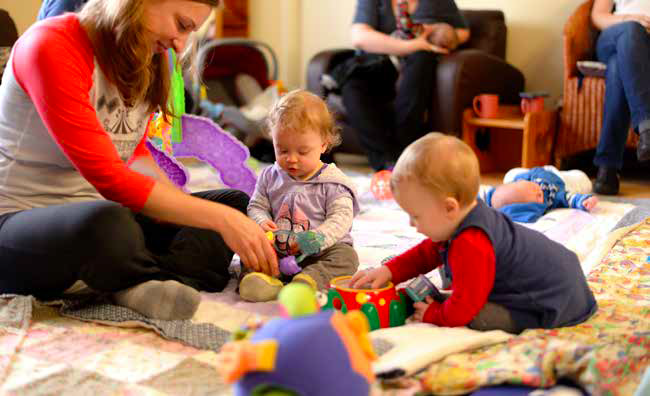 Two babies are playing with an adult